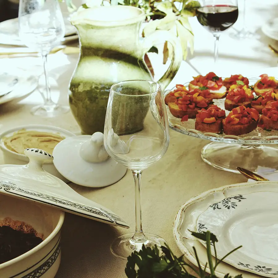 Photo détaillée d'une table avec de la nourriture, des verres et du vin.